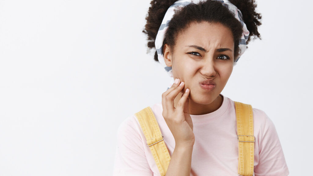 Photo of young girl holding her cheek wondering if she is dealing with a dental abscess.